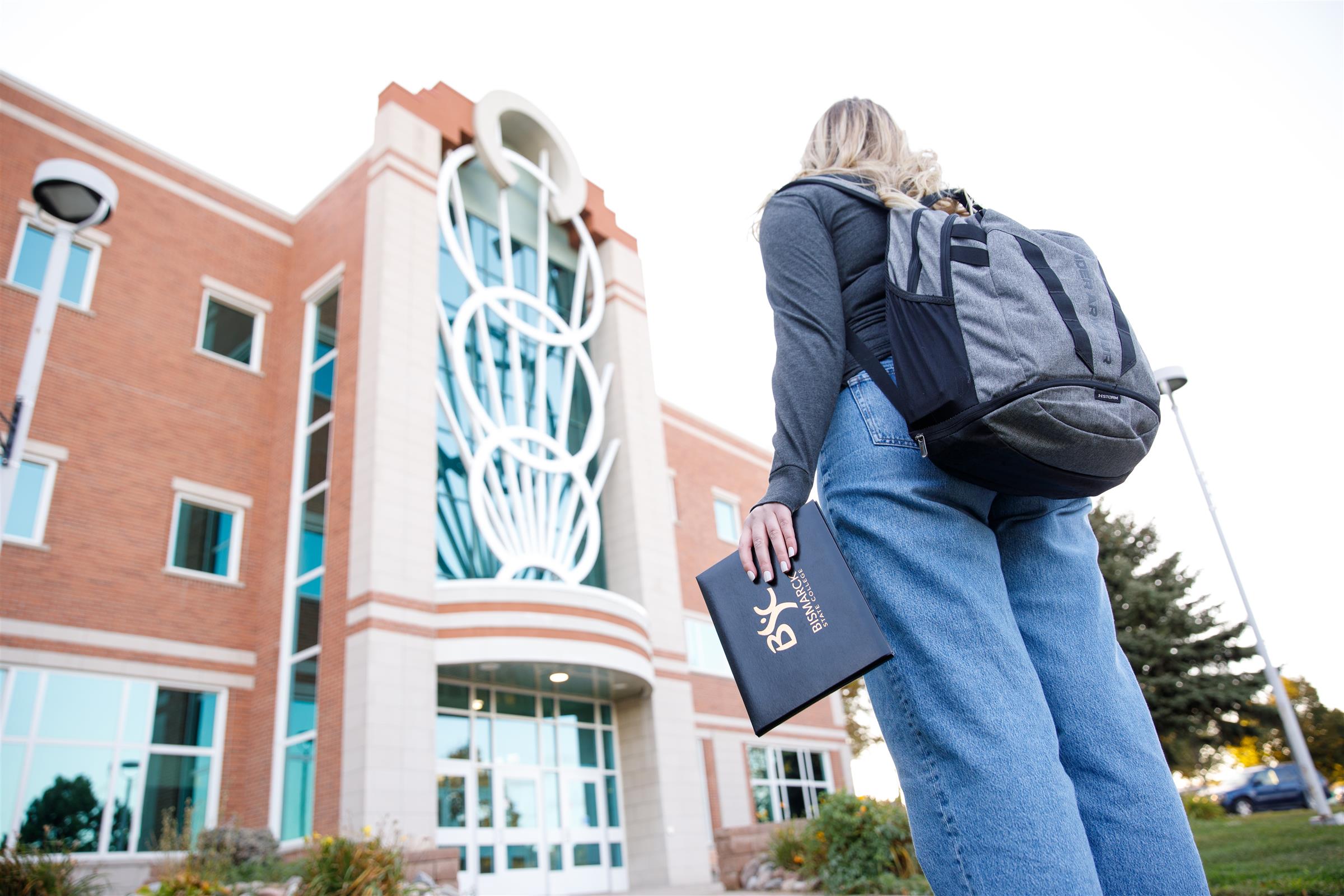 Student holding a BSC degree, standing in front of the Jack Science Center at BSC.