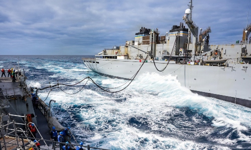 Navy boat off the shore with waves.