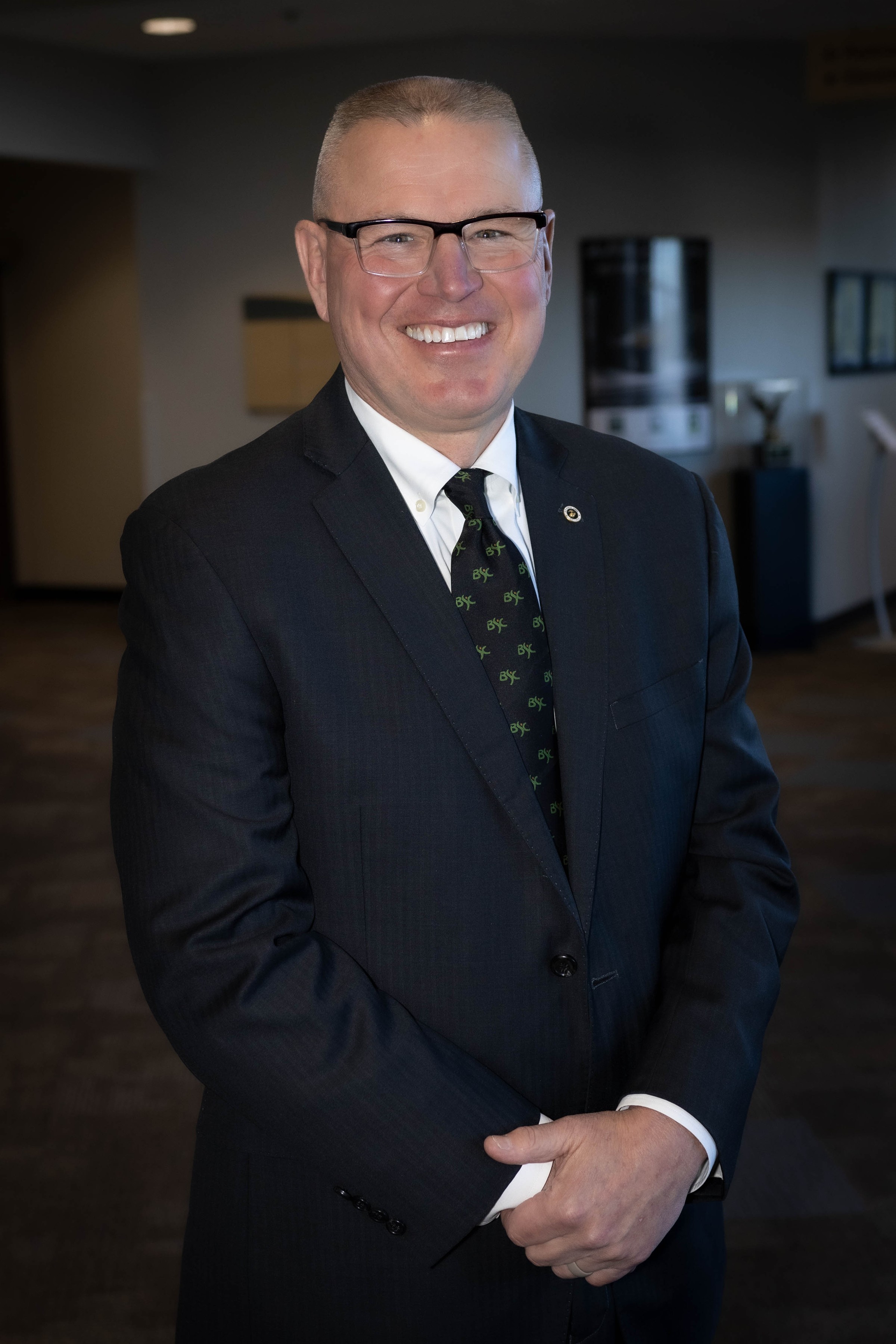 Man wearing a black blazer with a tie that has BSC logo