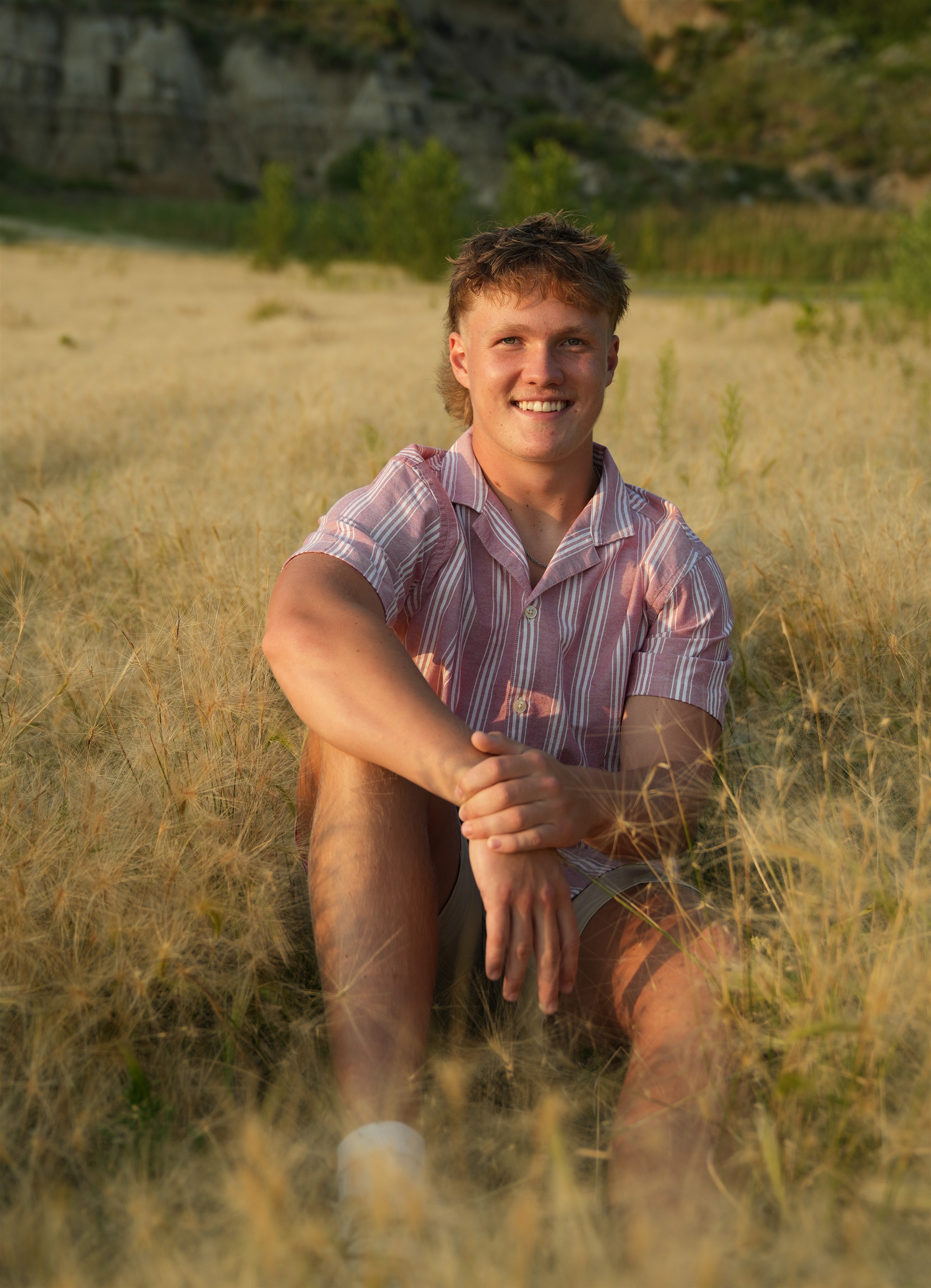 Young man sitting in field at sunset